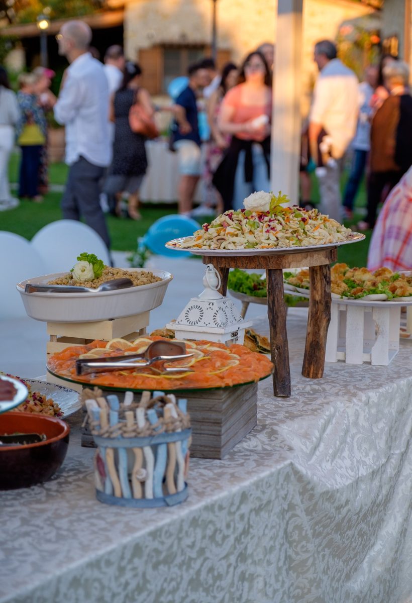 Buffet allestito all'aperto con alzate in legno, insalate e piatti freddi